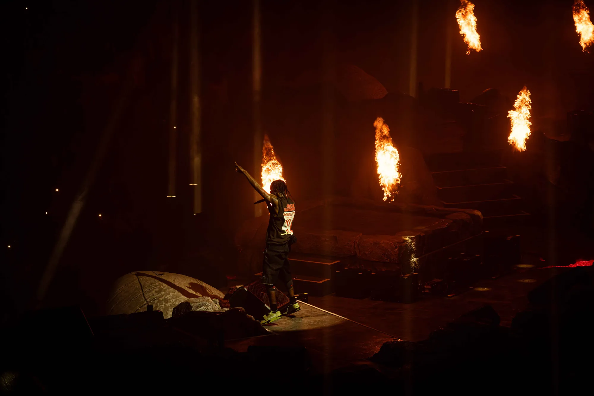 Travis Scott performing with dramatic stage lighting