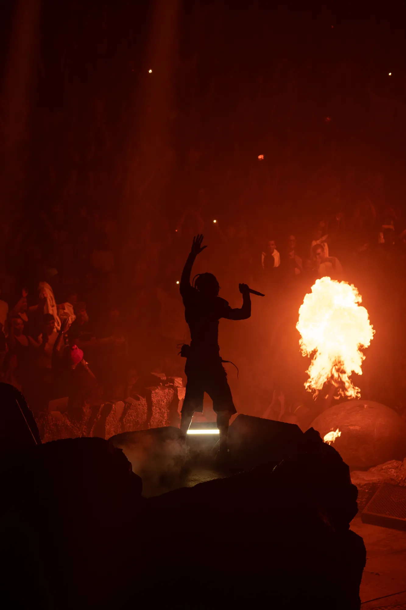 Travis Scott performing with dramatic stage lighting
