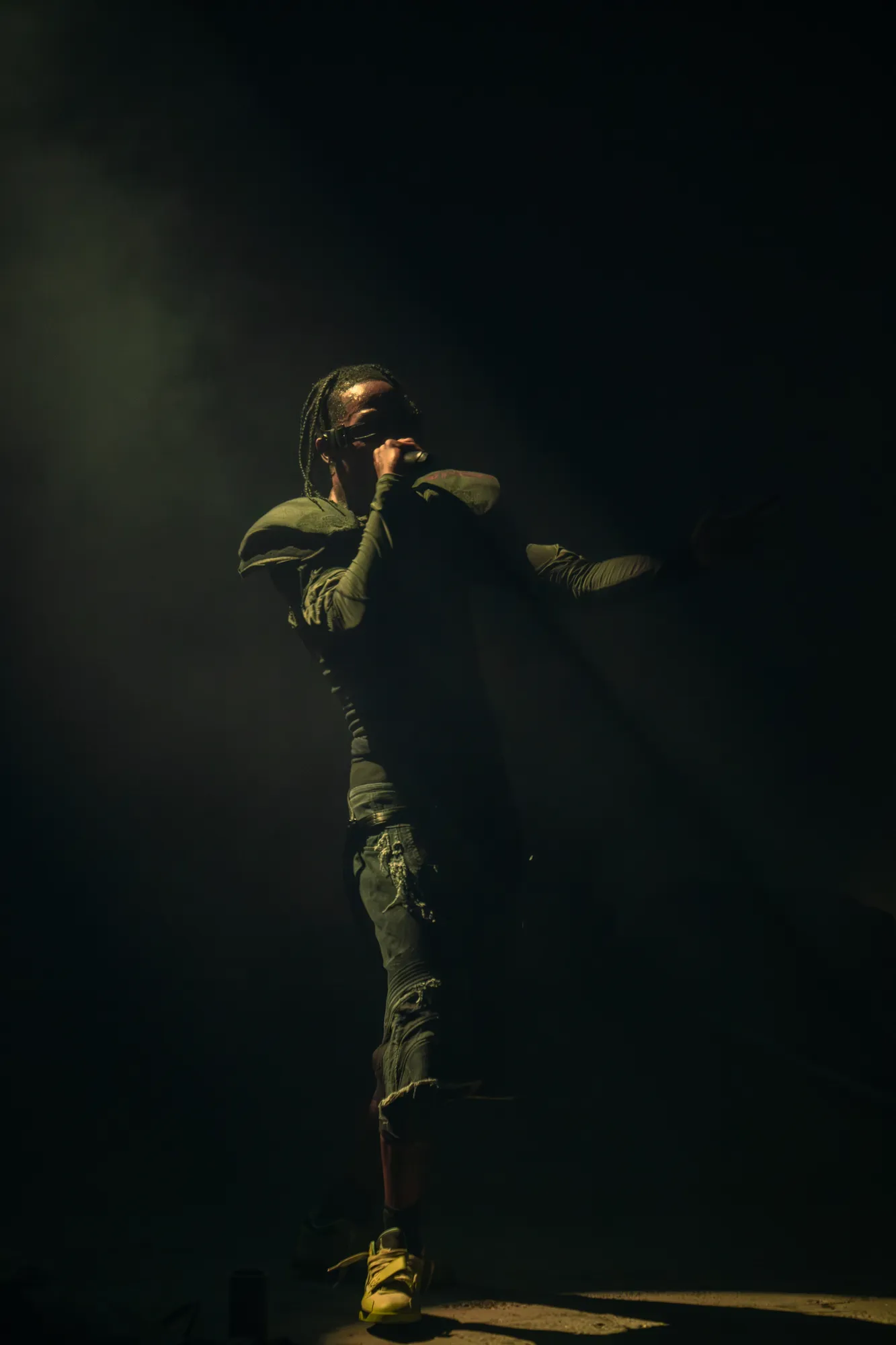 Travis Scott performing with dramatic stage lighting