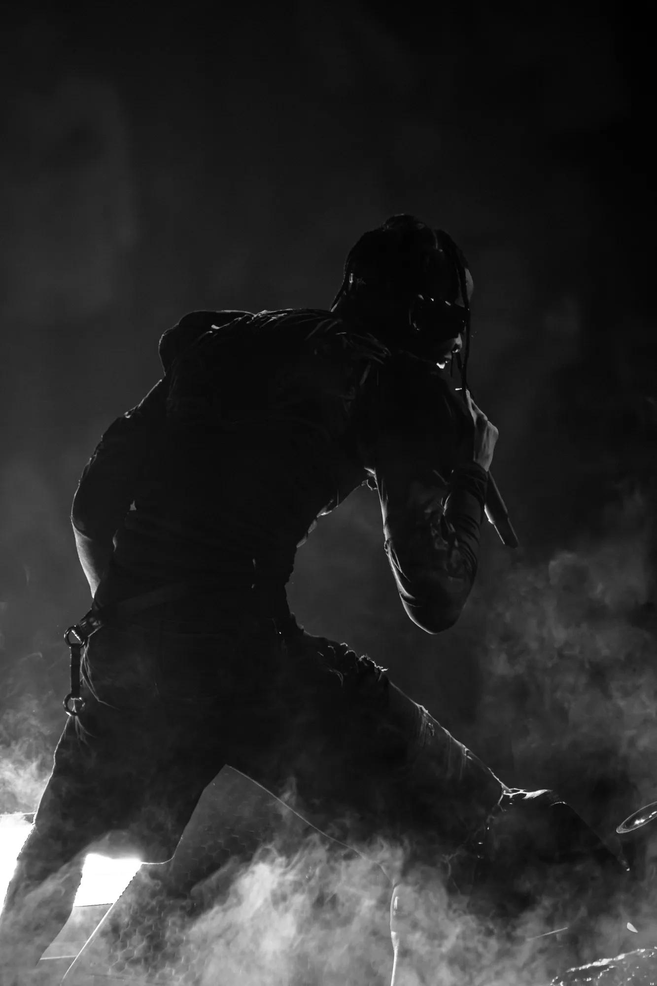 Travis Scott performing with dramatic stage lighting